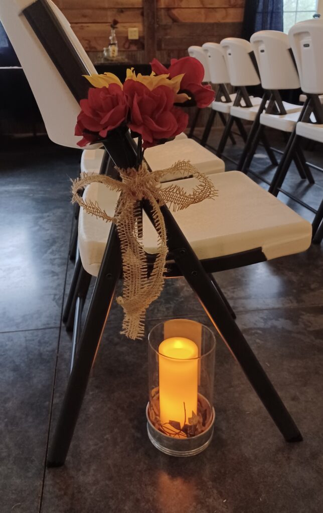 A wedding aisle chair decorated with a sunflower and red rose bouquet for unique rustic wedding inspiration at Country Charm Venue
