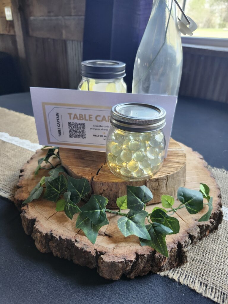 Rustic wedding centerpiece with mason jars, ivy on a wood slice, and a DOTS memory app QR code card