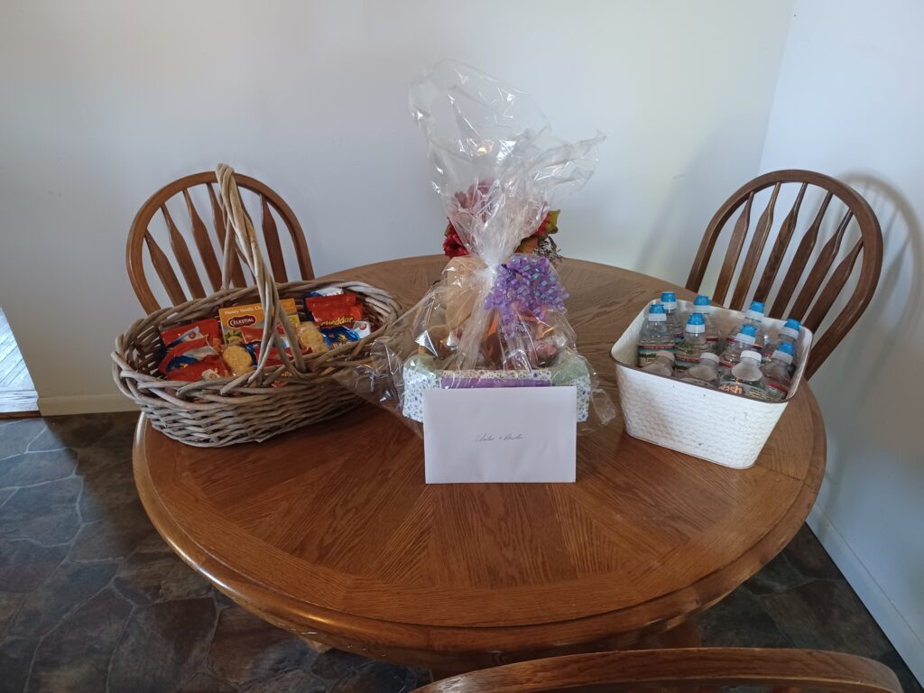 A gift basket and baskets with snacks and bottled water on the table at Country Charm Event Venue.