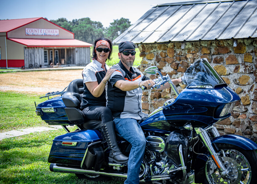 Engagement couple posing on a Harley Davidson motorcycle at Country Charm Event Venue