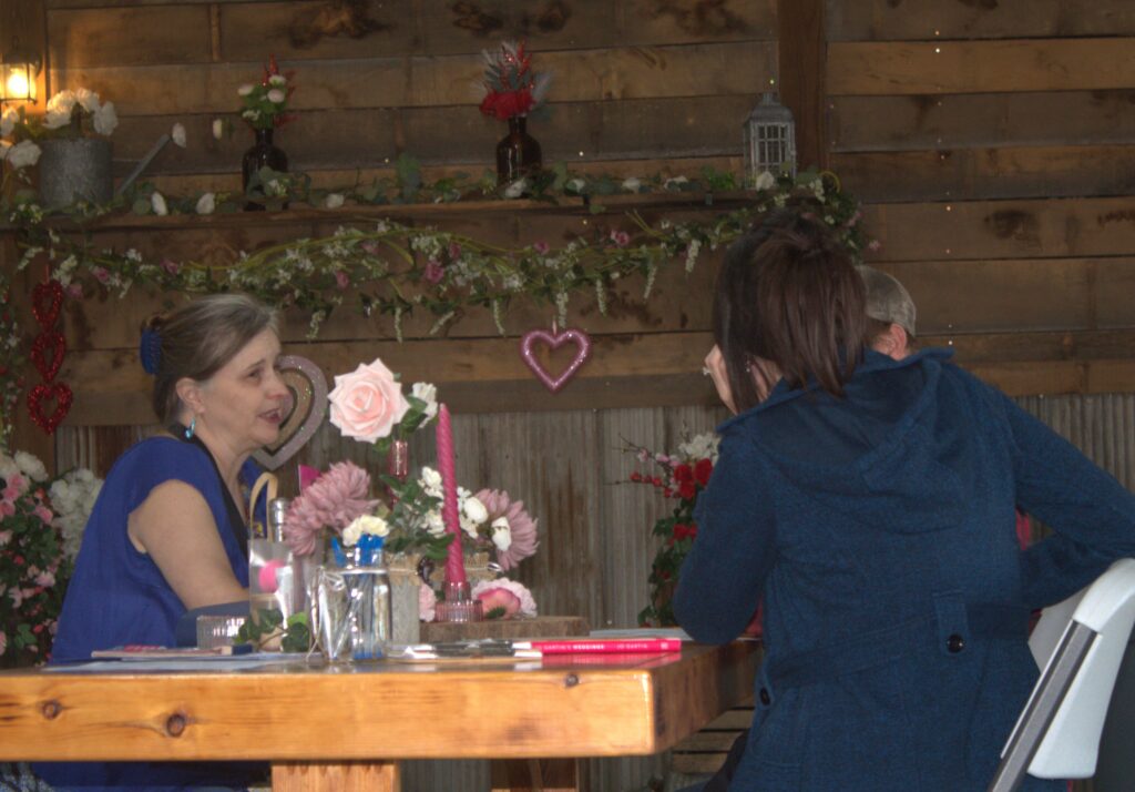 Country Charm Venue owner getting to know a couple at the farmhouse table.